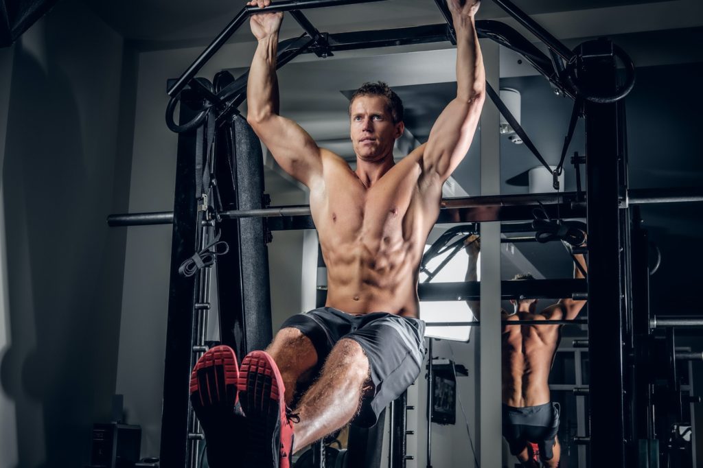 A man doing abs workouts on pull up bar.
